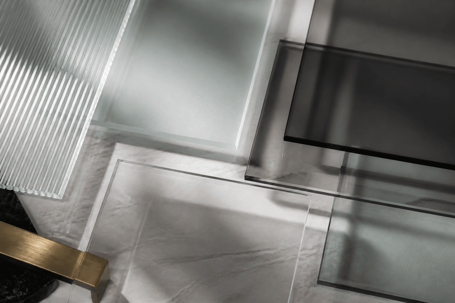 Overlapping clear, tinted, frosted, fluted and smoked glass panels on stone