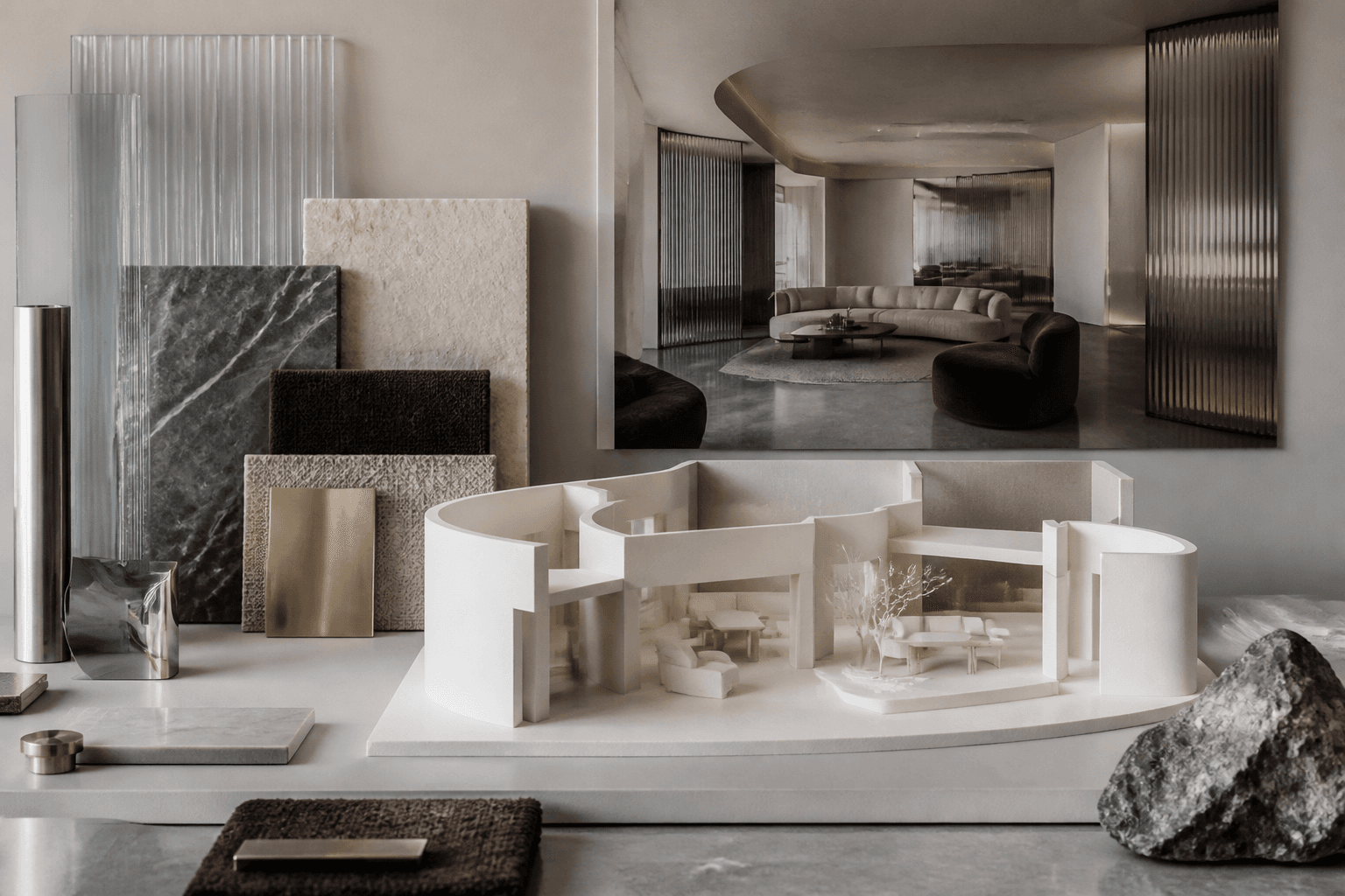 A sculptural interior concept model with fluted glass, stone samples and a modern interior render behind it
